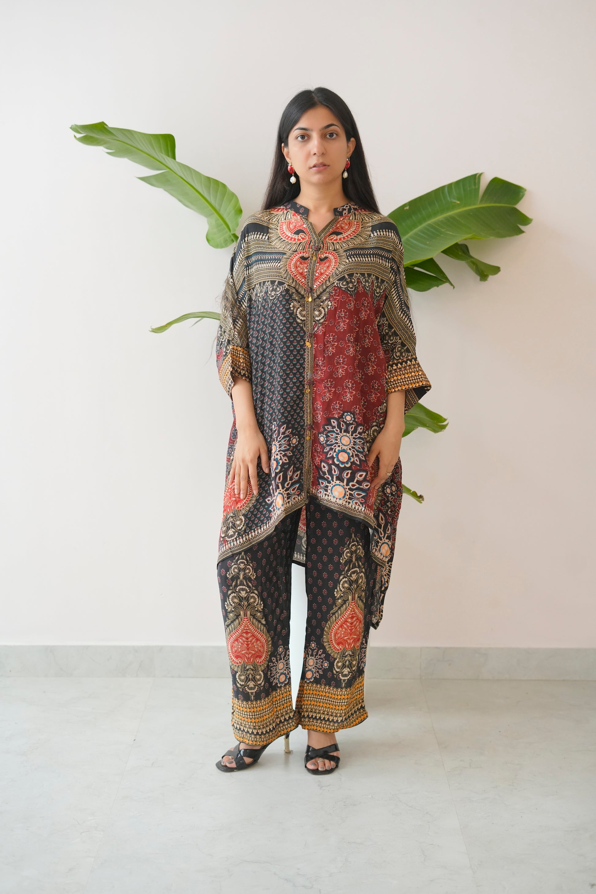 Woman wearing a patterned outfit with large green leaves in the background
