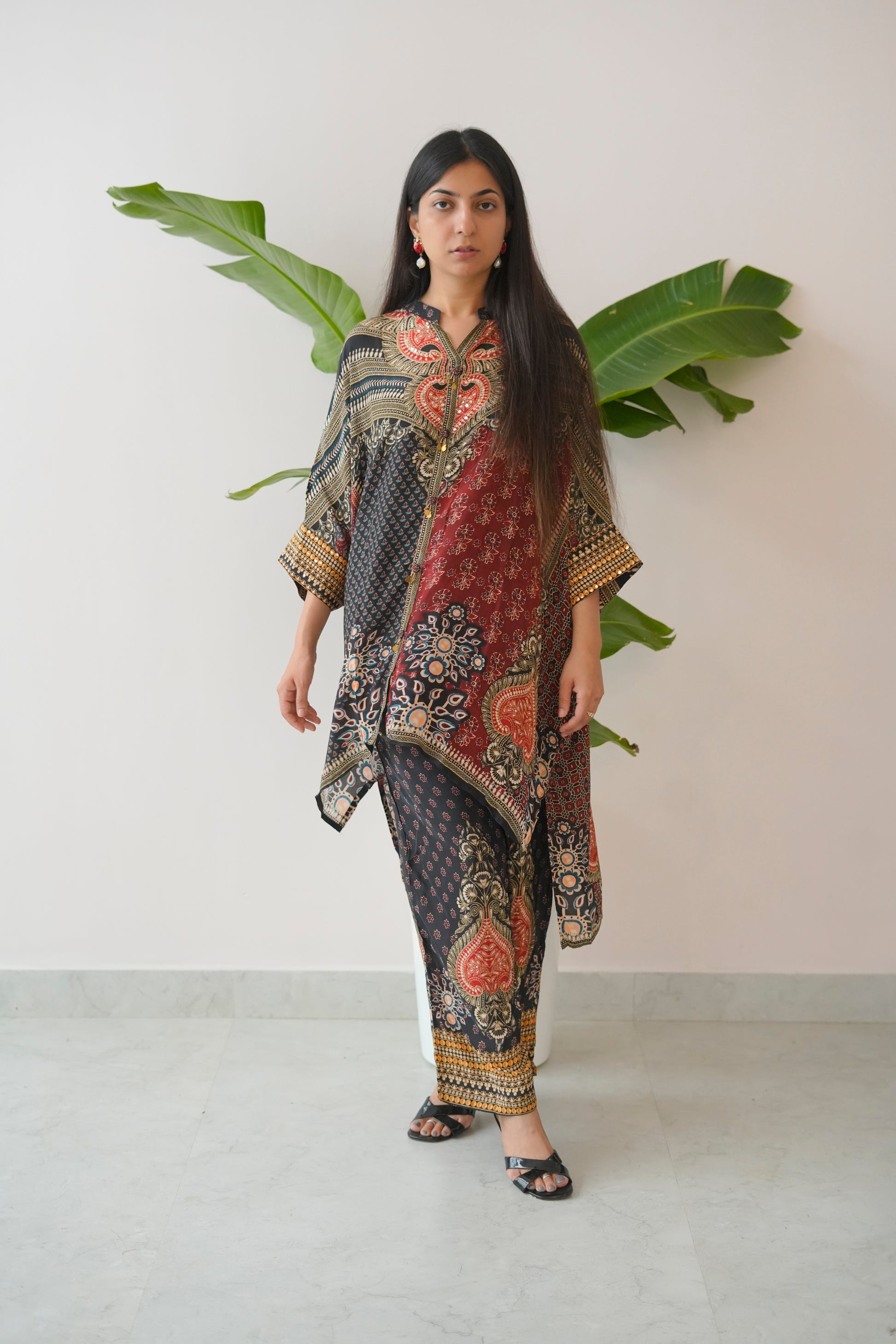 Woman wearing a patterned outfit with a white background and green leaves.