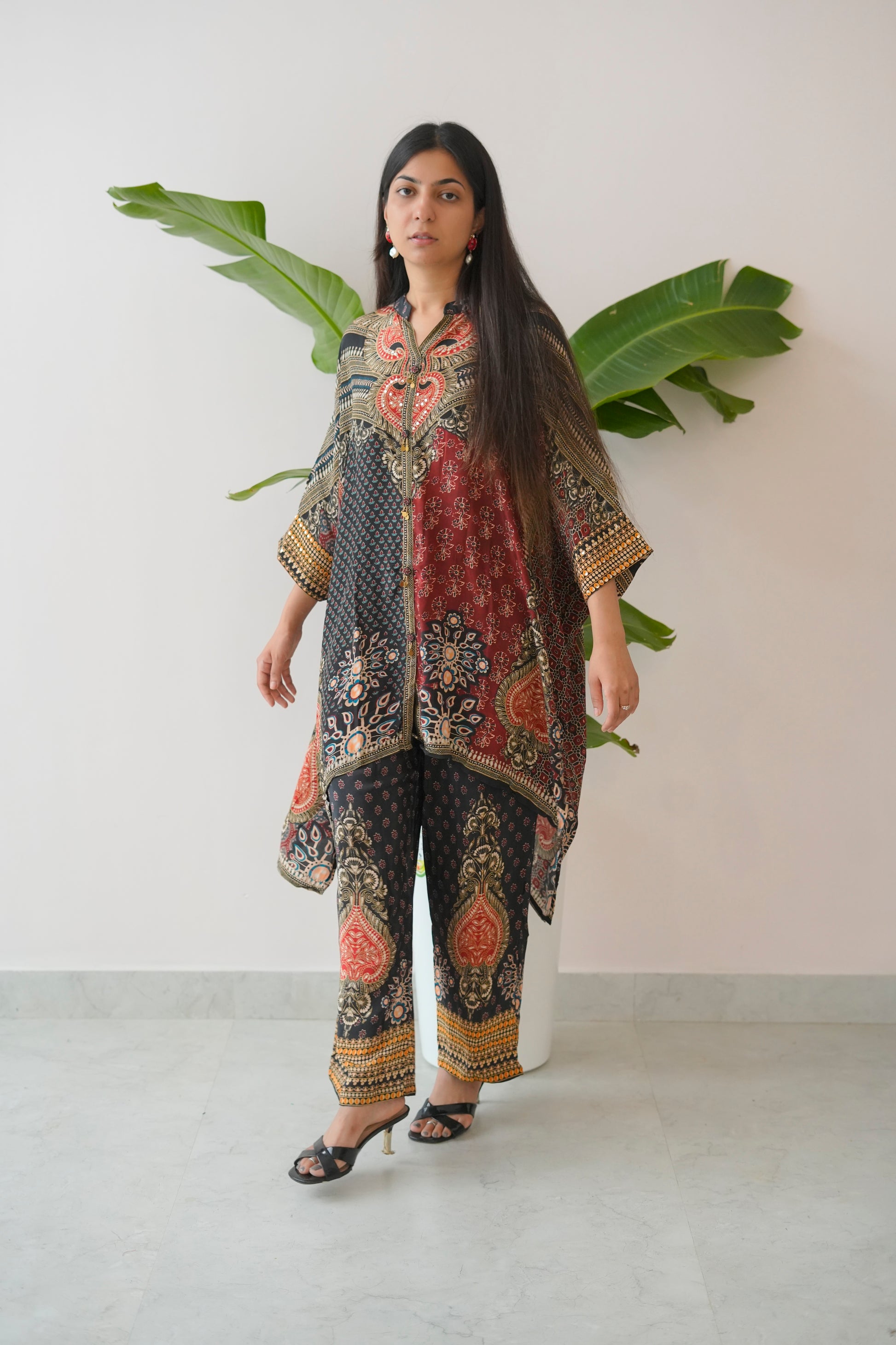 Woman wearing a patterned outfit with large leaves in the background
