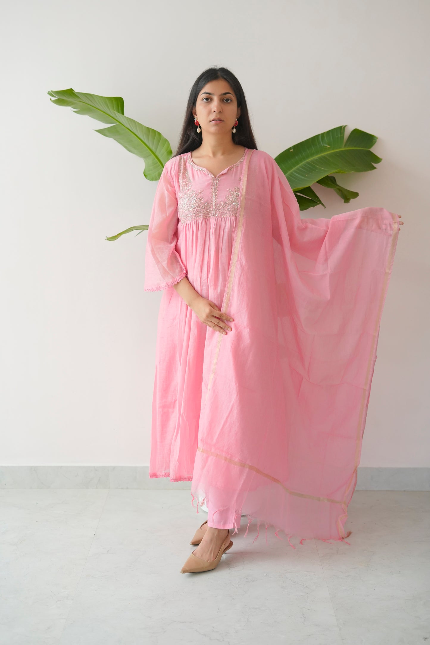 Woman wearing a pink nightgown with a white lace bralette against a white background