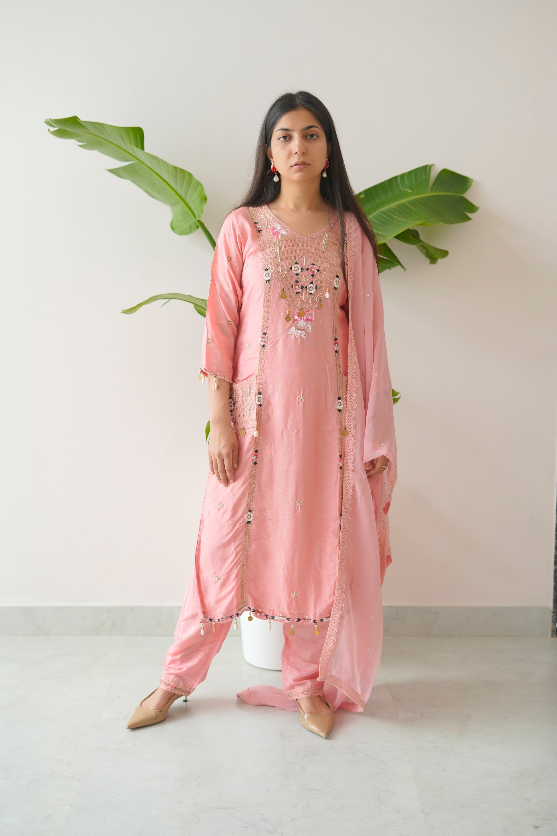 Woman wearing a pink traditional outfit with floral embroidery against a white background