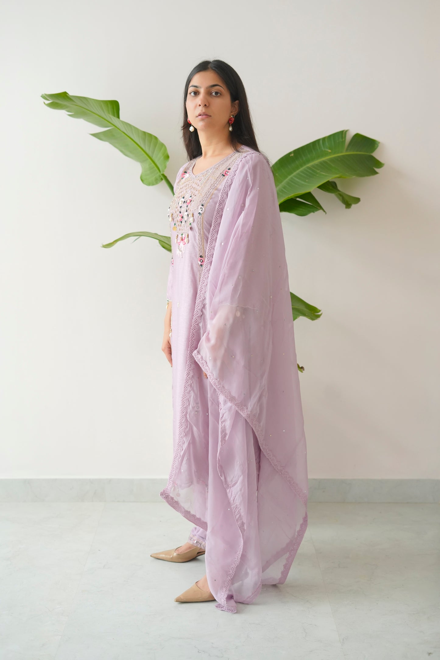 Woman wearing a light purple traditional outfit with a white background and green leaves.
