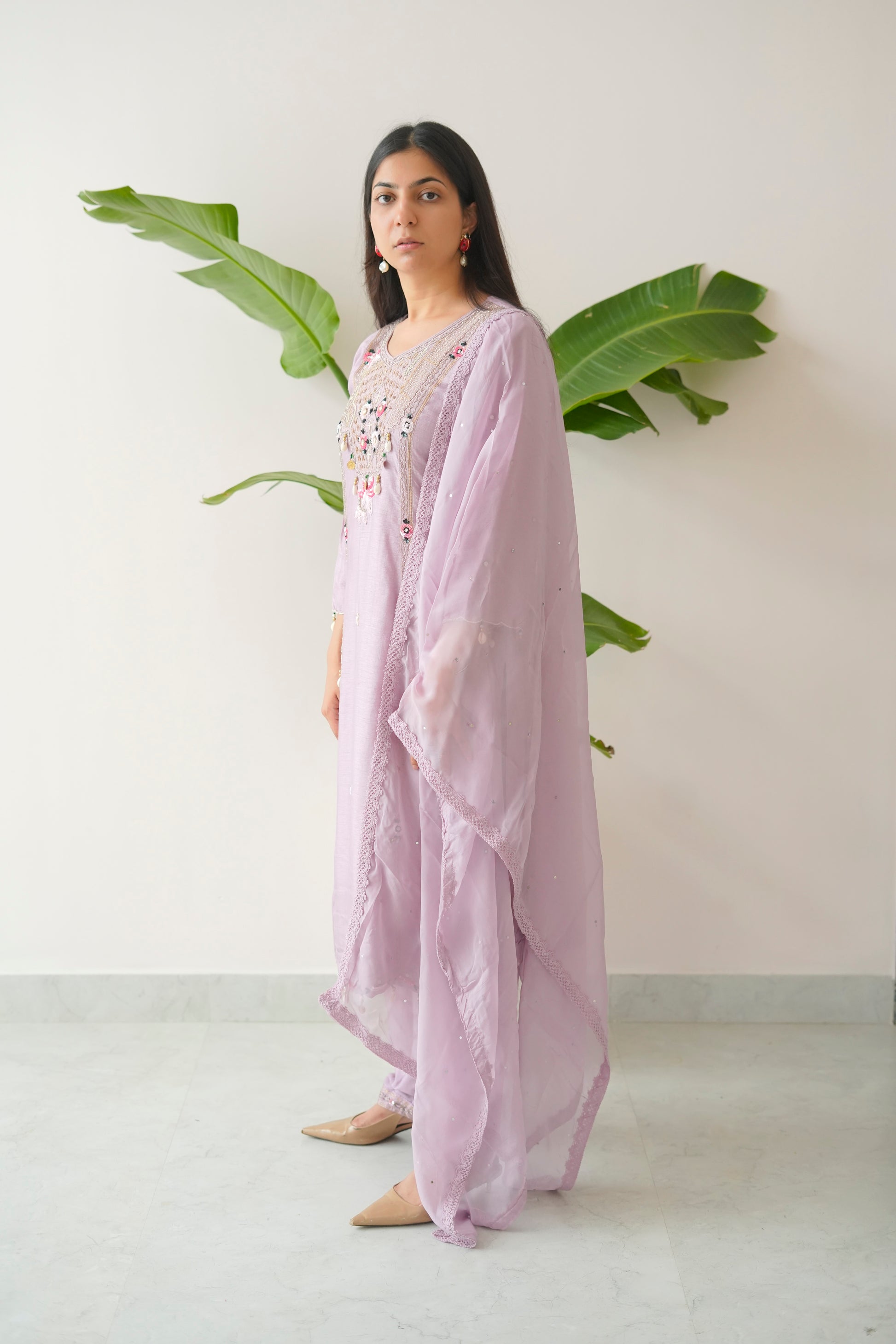 Woman wearing a light purple outfit with floral embellishments against a white background