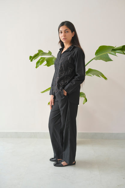 Woman wearing a black outfit standing in front of a plant with a white background