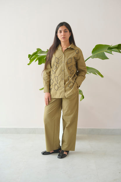 Person wearing a green outfit standing in front of a plant with a white background