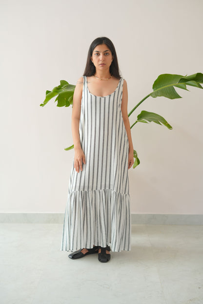 Woman wearing a striped dress standing indoors with plants in the background