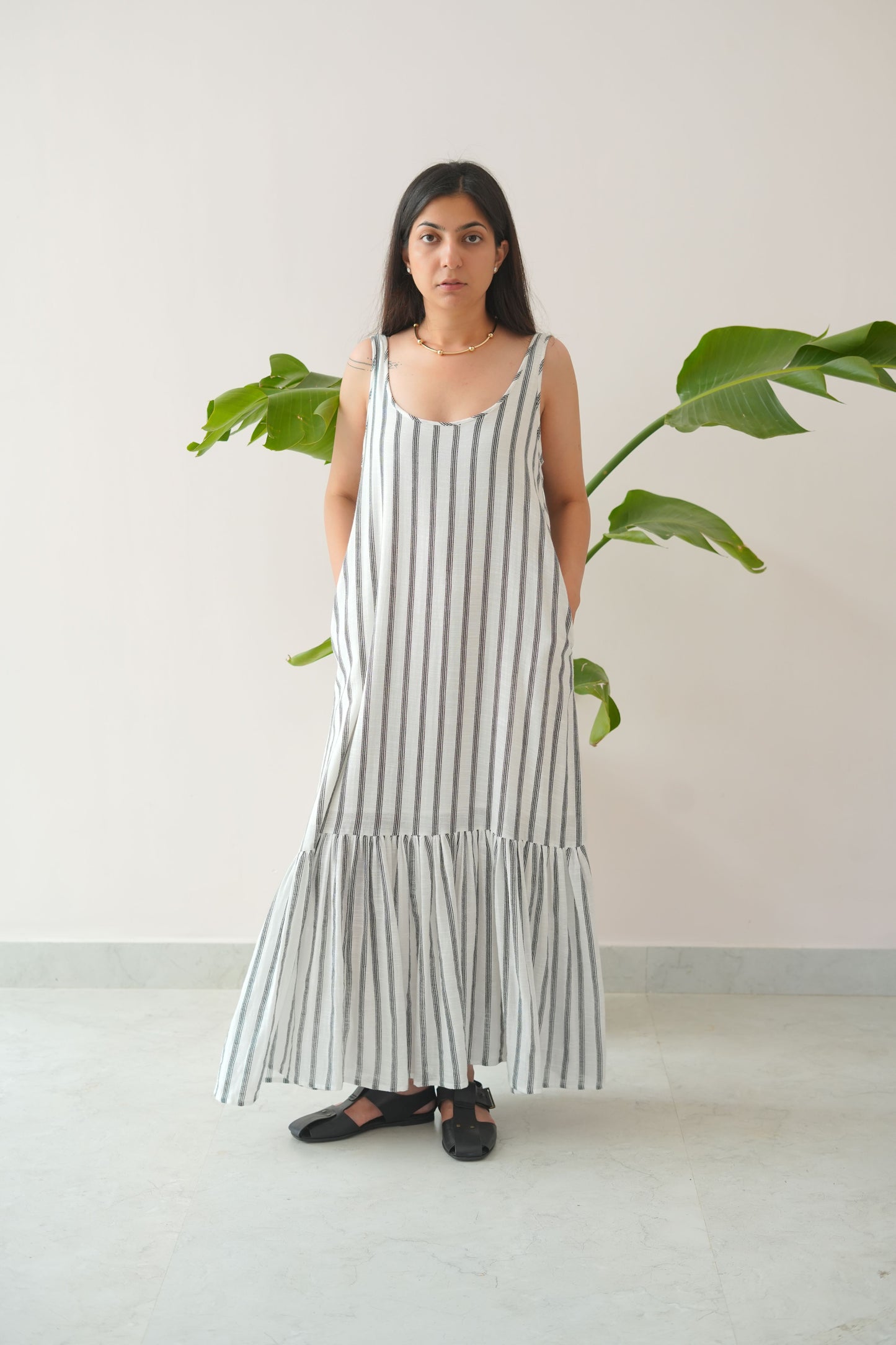 Woman wearing a long, light-colored dress with vertical stripes indoors.