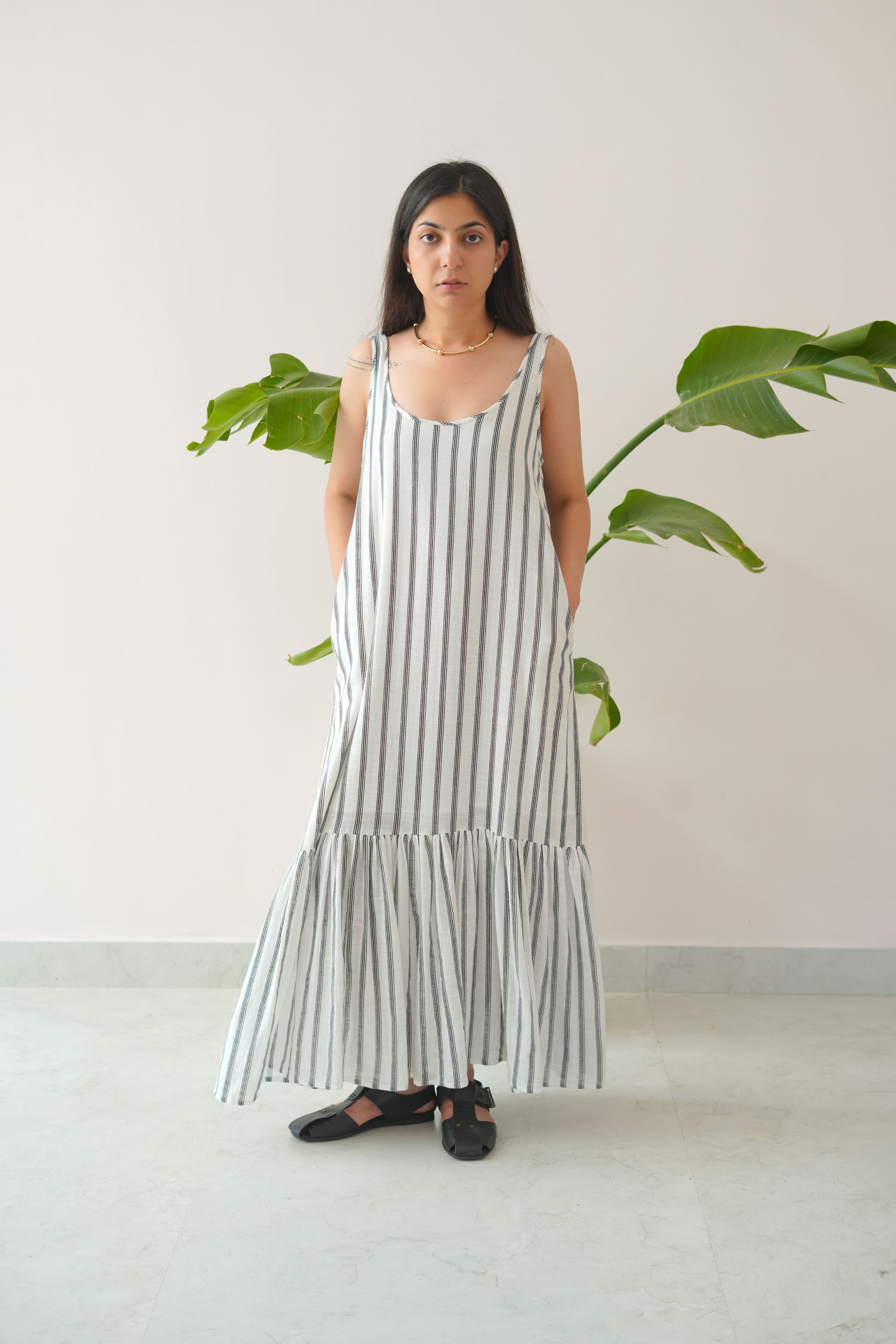 Woman wearing a long, light-colored dress with vertical stripes indoors.
