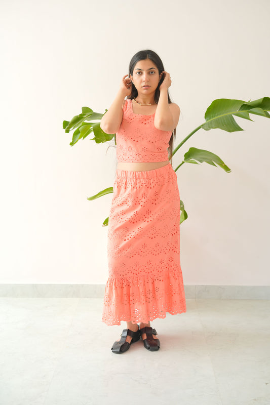 Woman in a pink dress standing next to a plant on a white background