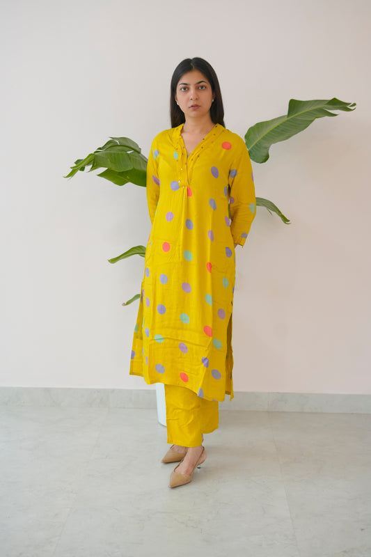 Woman wearing a yellow outfit with colorful polka dots against a white background