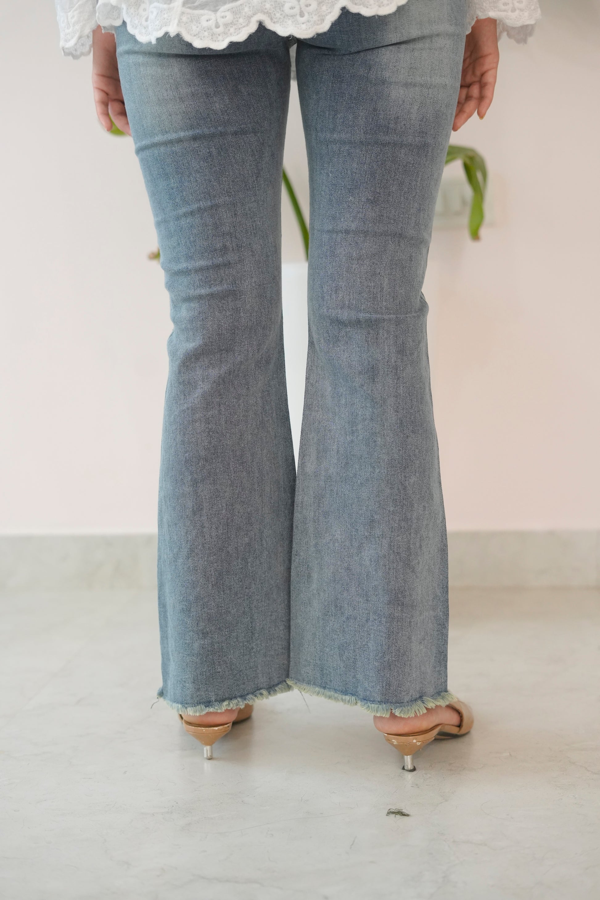 Person wearing light blue flared jeans on a plain background