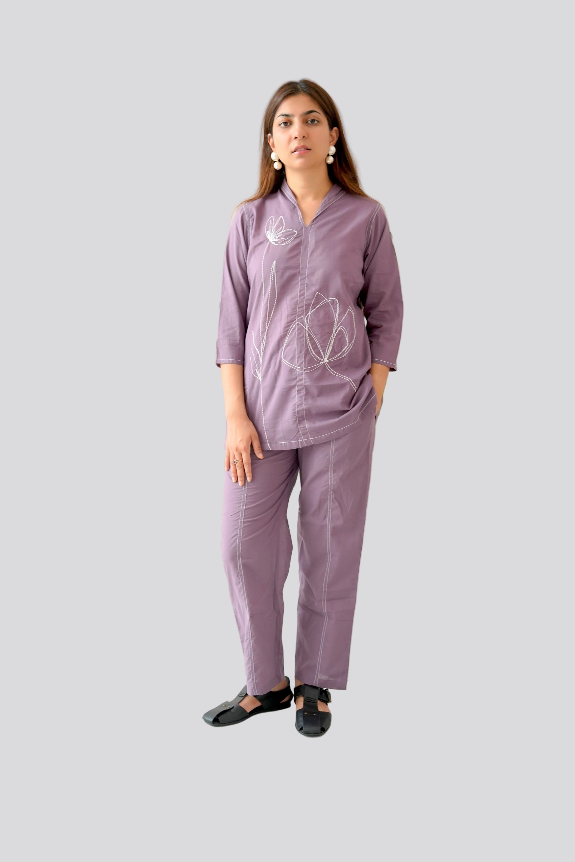 Woman wearing a purple outfit with a heart design on a plain background