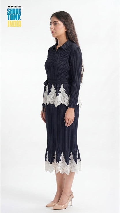 Woman wearing a navy dress with white lace details on a white background