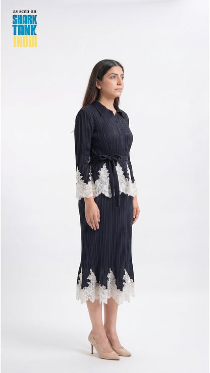 Woman wearing a navy dress with white lace details on a white background