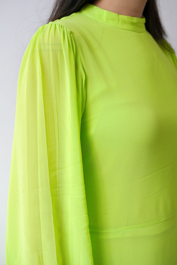 Close-up of a bright green dress with long sleeves on a plain background