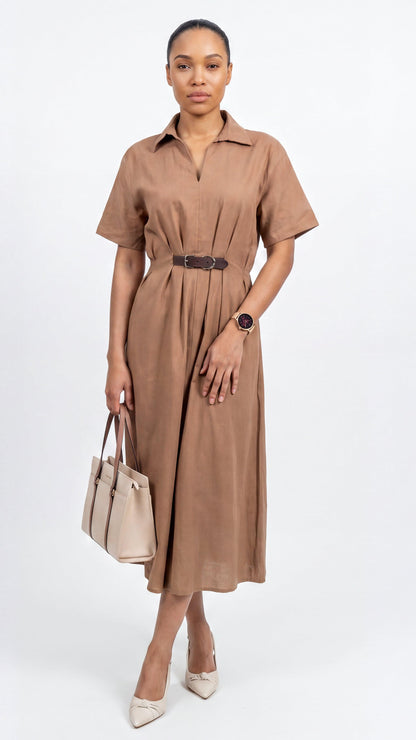 Woman wearing a brown dress with a belt, holding a beige handbag on a white background