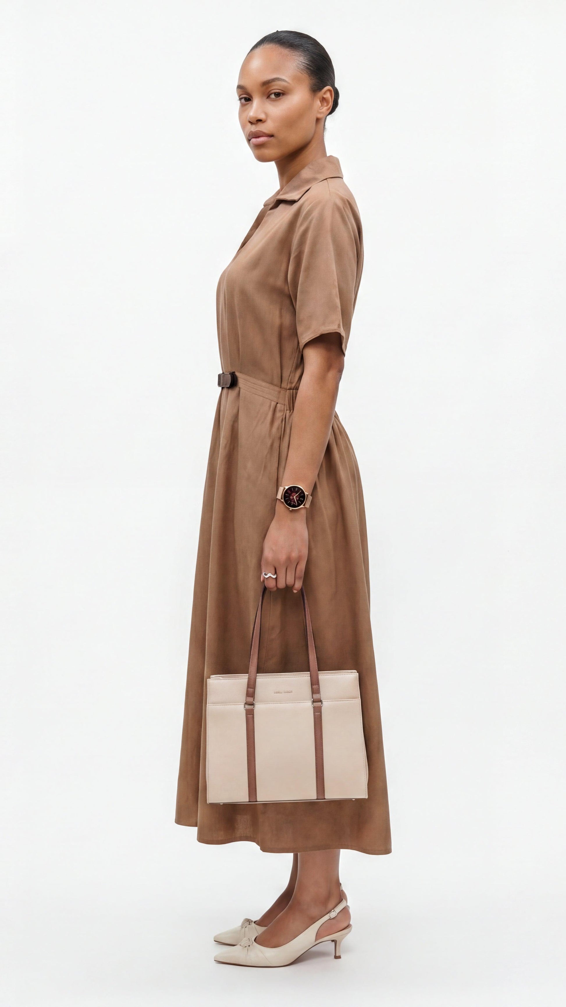 Woman wearing a brown dress holding a beige handbag on a white background