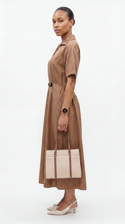 Woman wearing a brown dress holding a beige handbag on a white background
