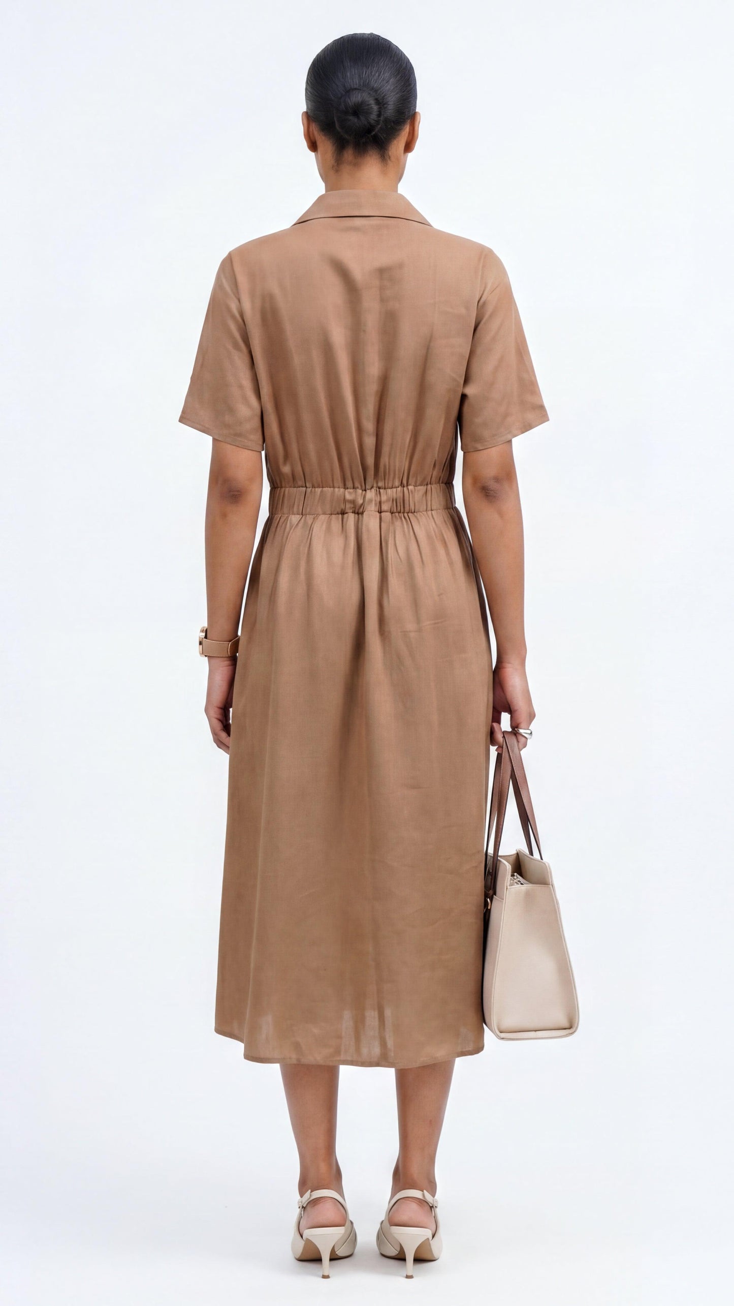 Woman wearing a brown dress holding a beige handbag on a white background