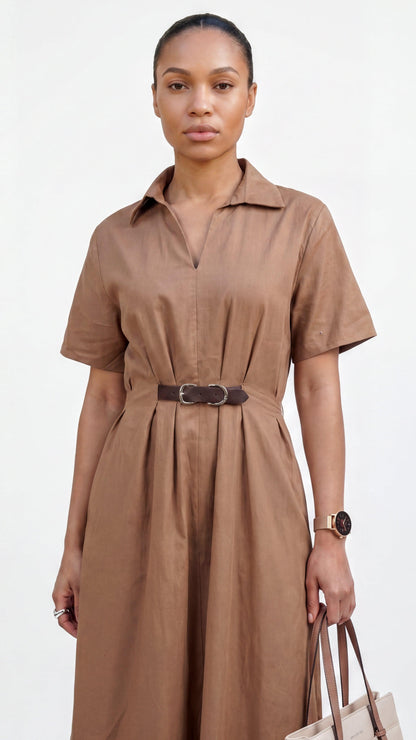 Woman wearing a brown dress with a belt, holding a beige handbag on a white background