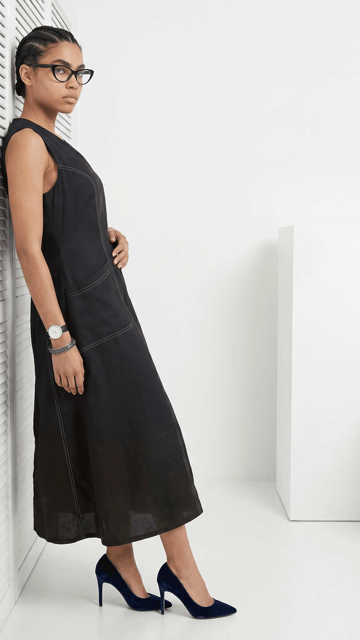 Woman wearing a black dress and high heels against a white background