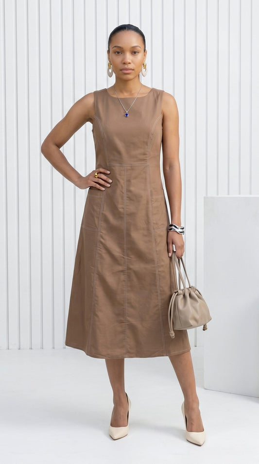 Woman wearing a brown dress holding a beige handbag against a white background