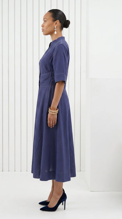 Woman wearing a long blue dress against a white background