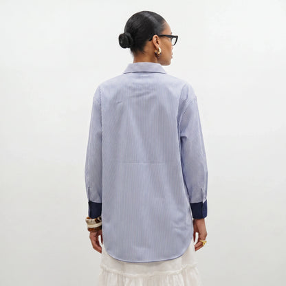 Person wearing a blue and white striped shirt against a white background