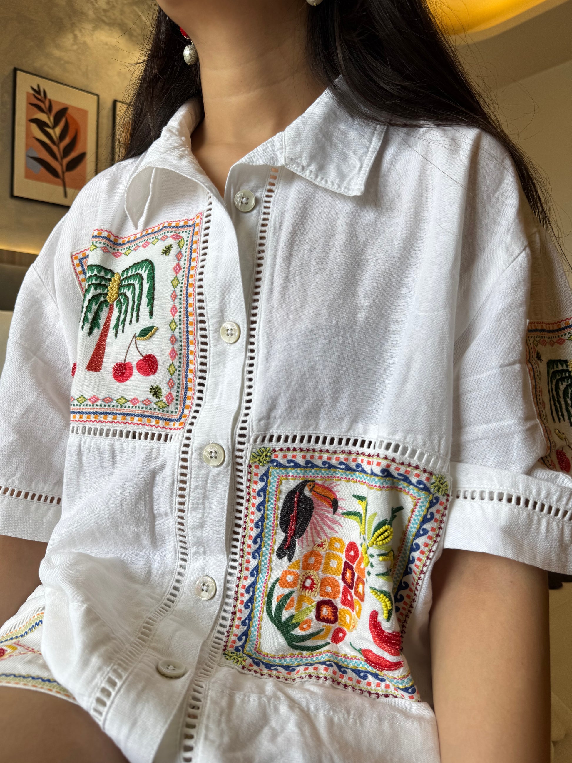White shirt with colorful embroidery on a blurred indoor background
