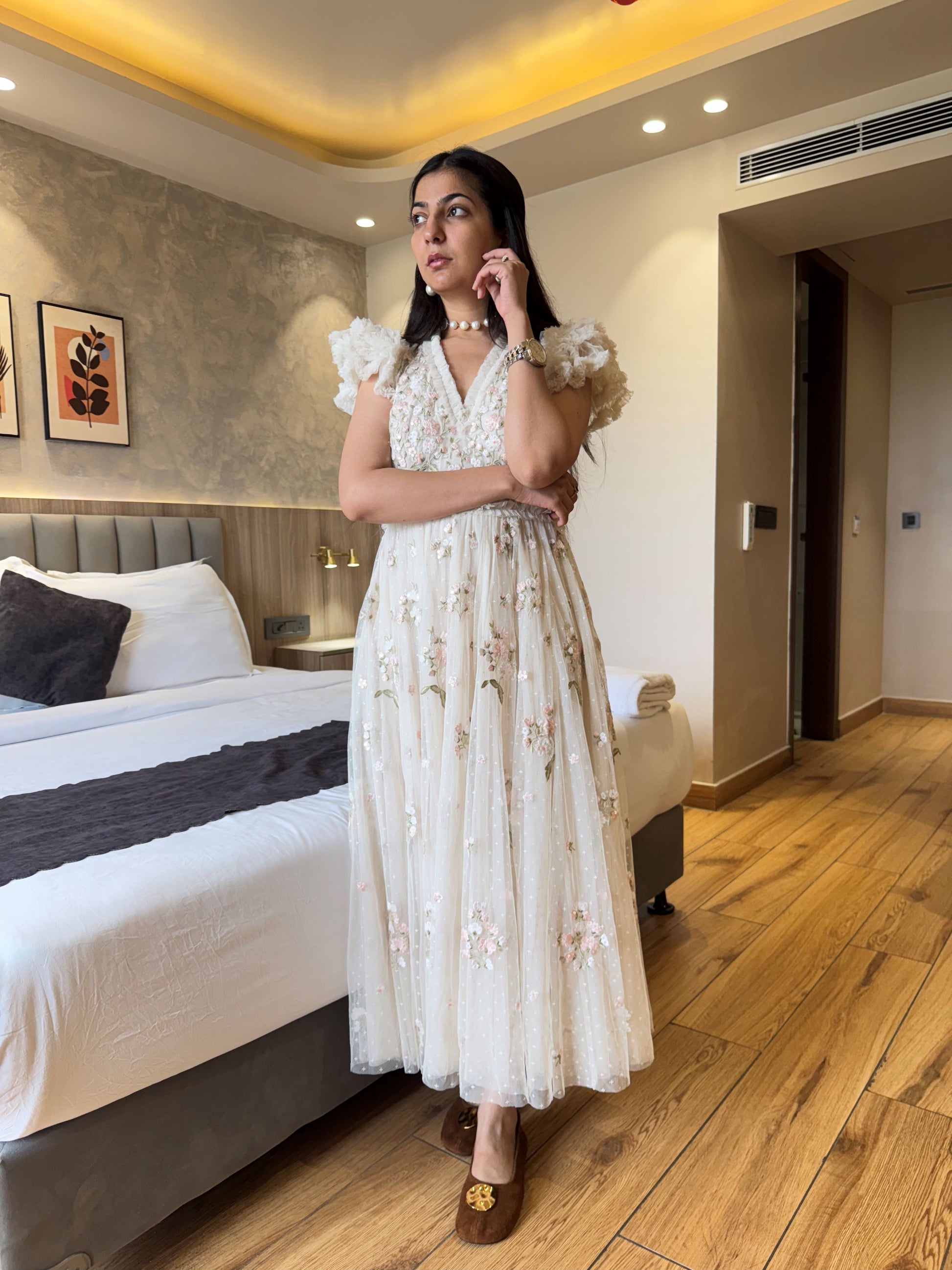 Woman in a white floral dress standing in a bedroom