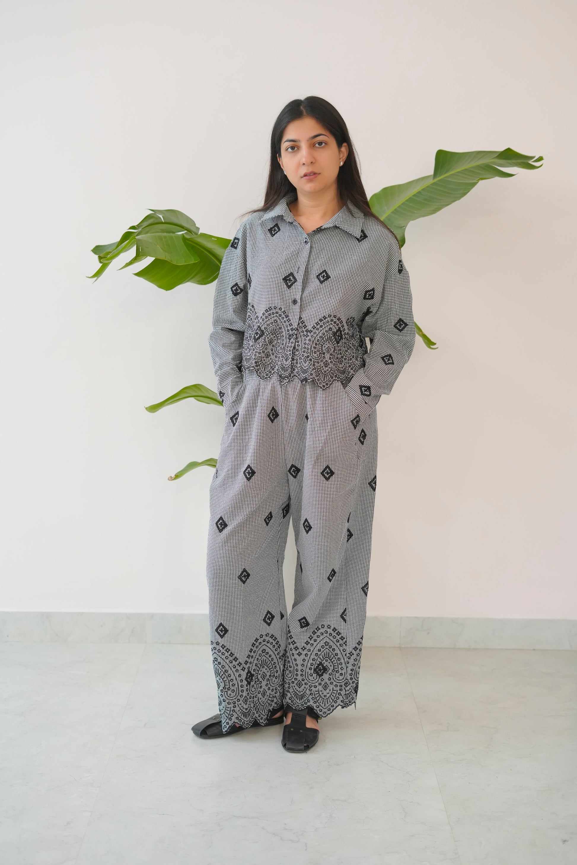 Woman wearing a gray outfit with black patterns in a minimal indoor setting