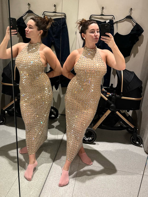 Woman trying on a sparkly gold dress in a fitting room.