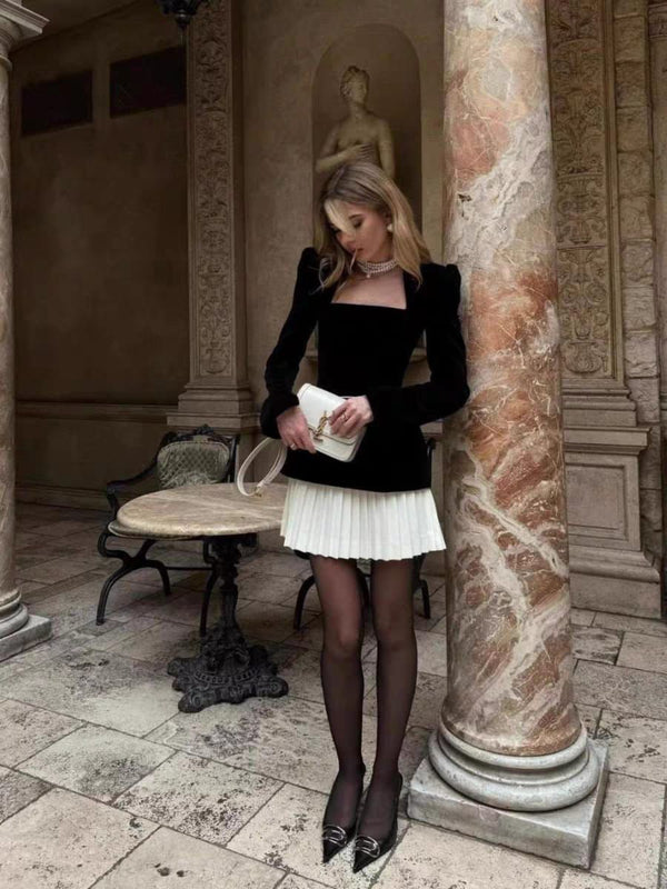 Woman in formal attire standing in an elegant outdoor setting with classical architecture.