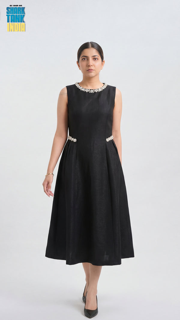 Woman wearing a black sleeveless dress with white embellishments on a white background