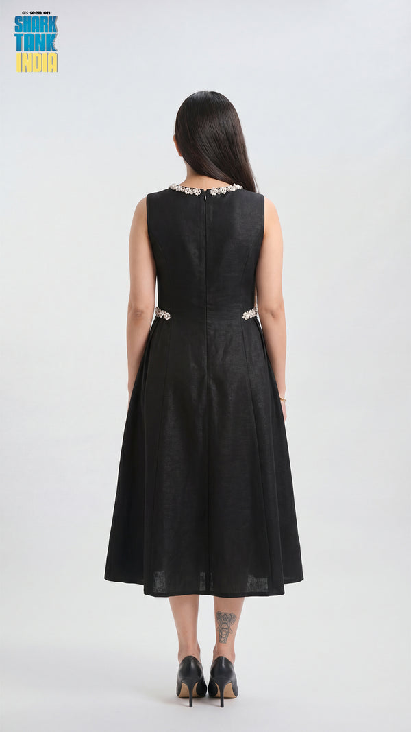 Woman wearing a black sleeveless dress with floral embellishments on a white background