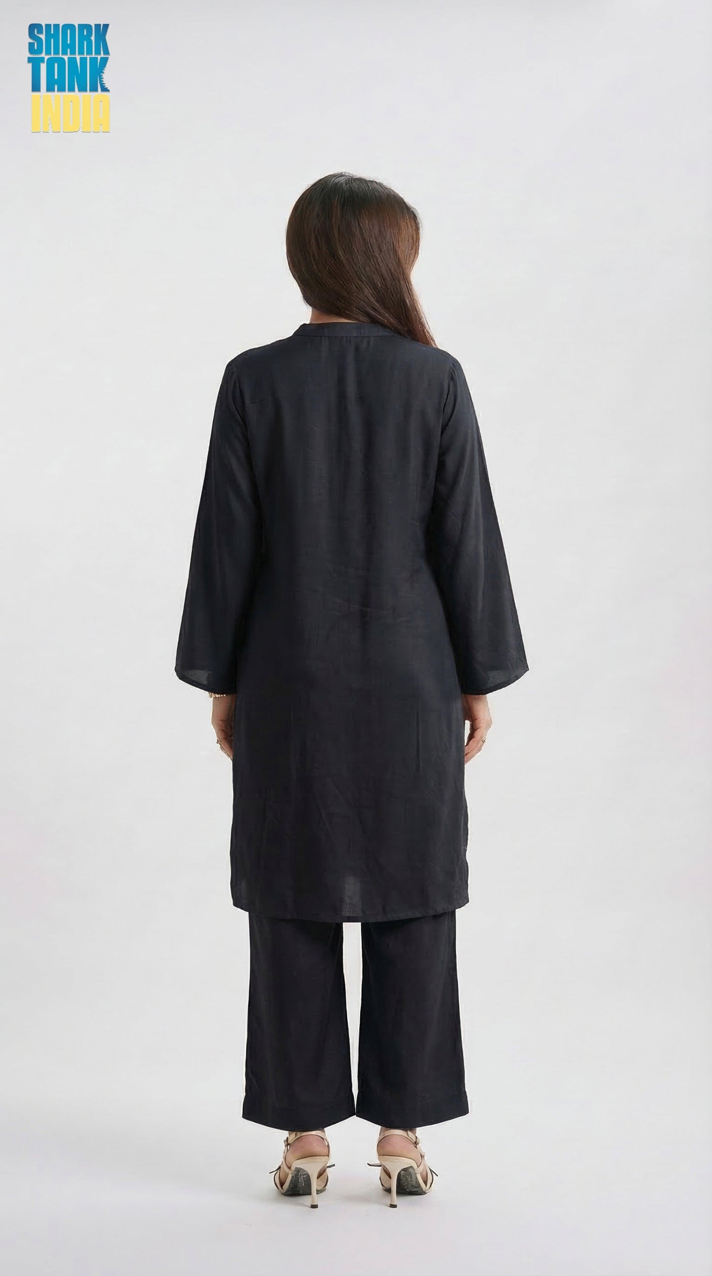 Person wearing a black outfit with wide-leg pants on a white background