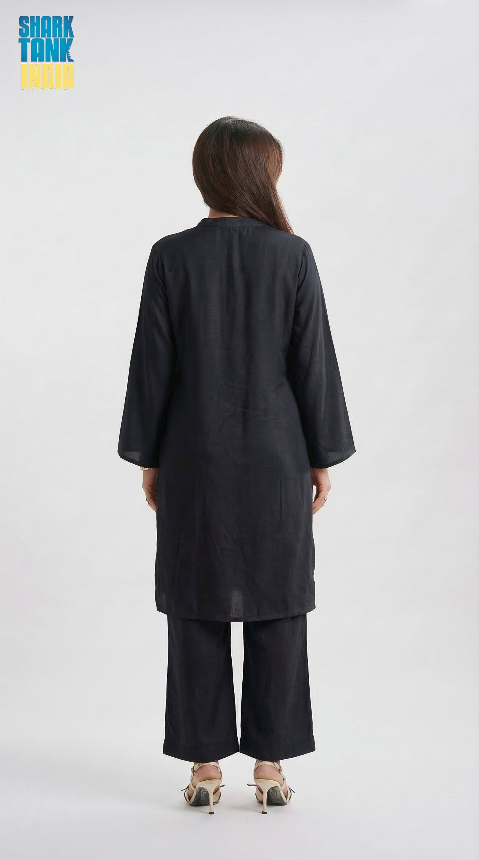 Person wearing a black outfit with wide-leg pants on a white background