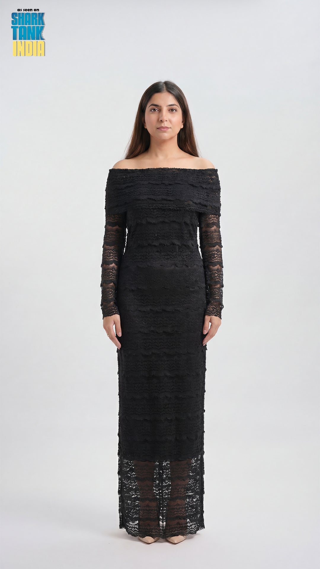 Woman wearing a black off-shoulder dress with long sleeves on a white background