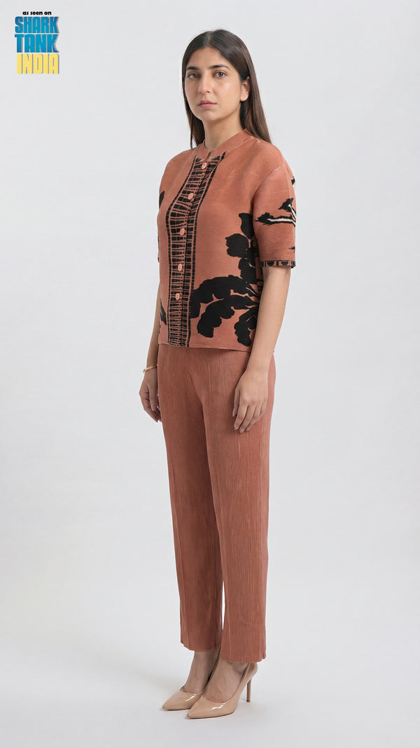 Woman wearing a brown outfit with black floral patterns on a white background