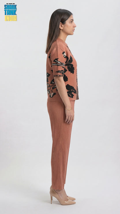 Woman wearing a pink outfit with black floral patterns on a white background