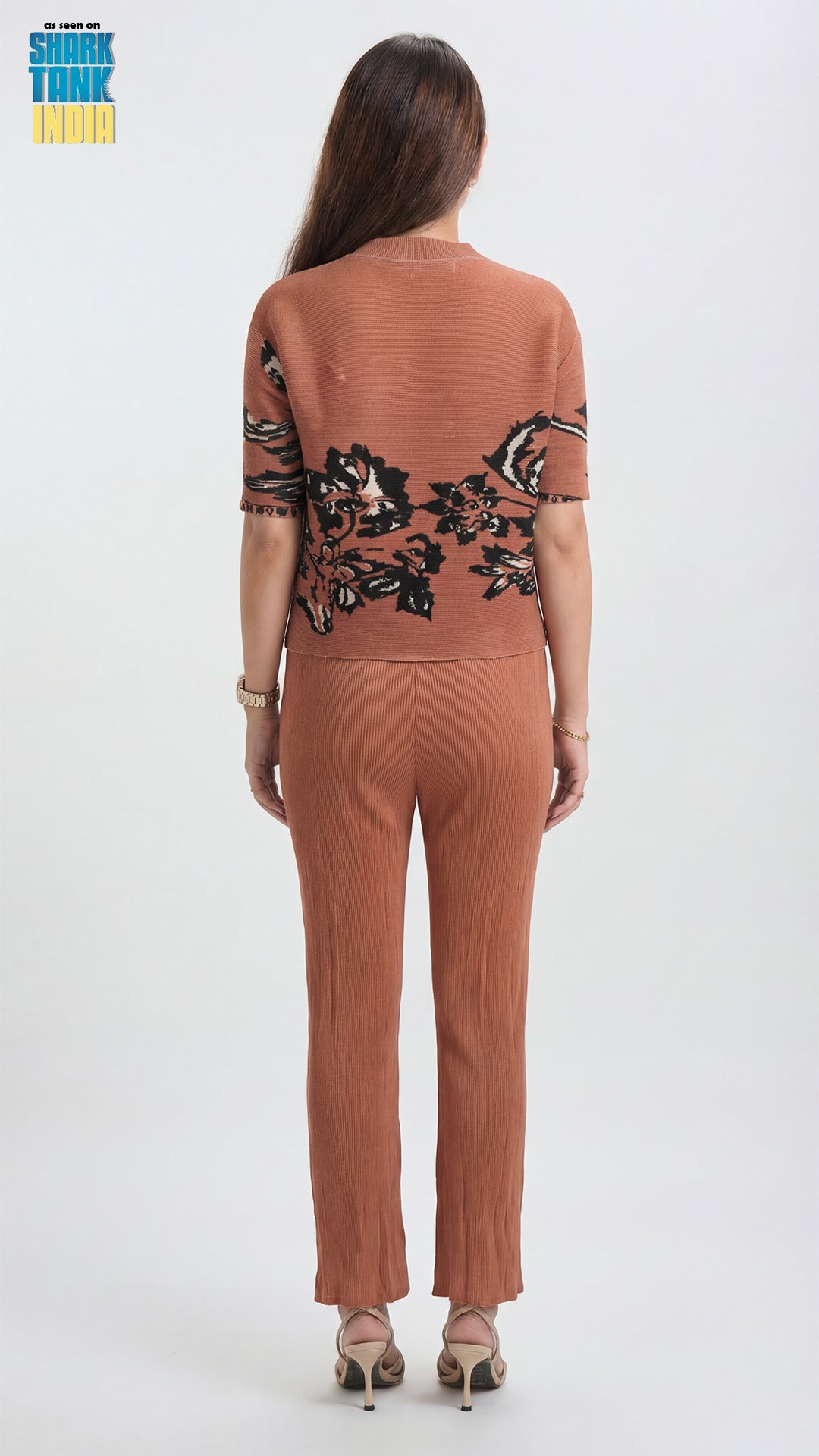 Woman wearing a brown jumpsuit with floral embroidery on a white background