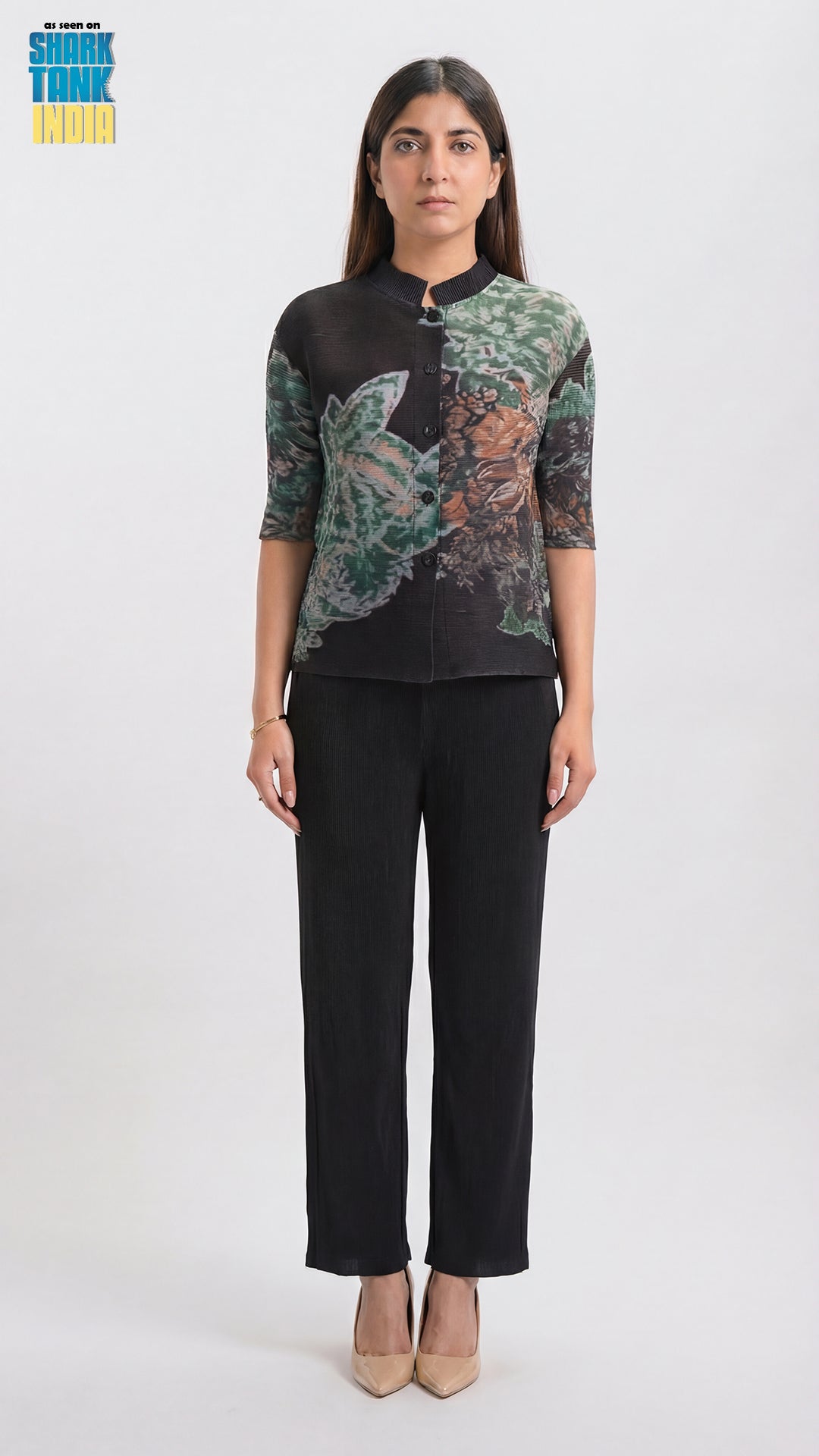 Woman wearing a black blouse with floral patterns and black pants on a white background