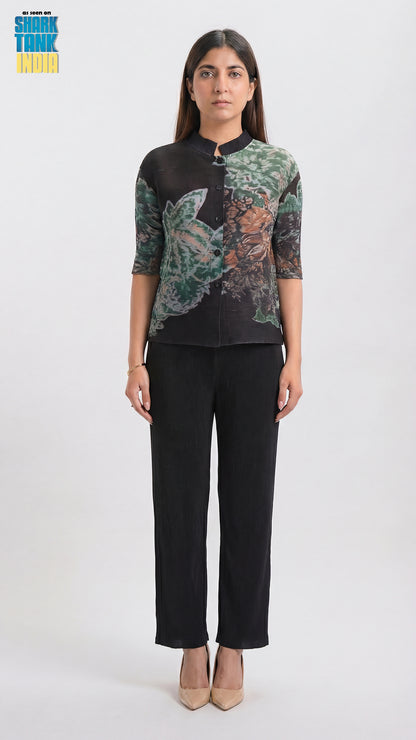 Woman wearing a black blouse with floral patterns and black pants on a white background