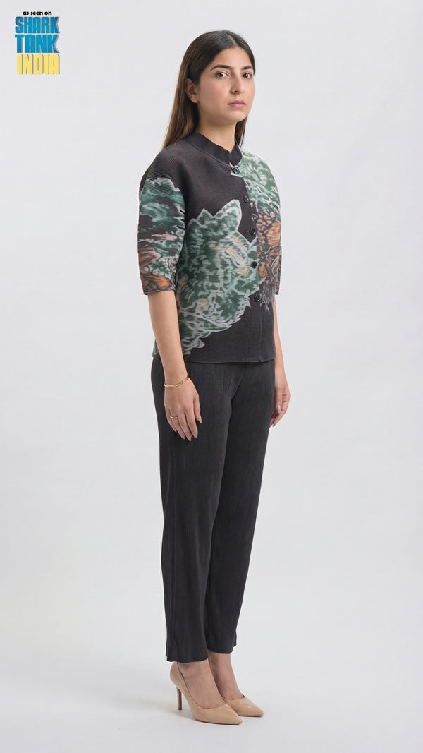 Woman wearing a patterned top and black pants on a white background