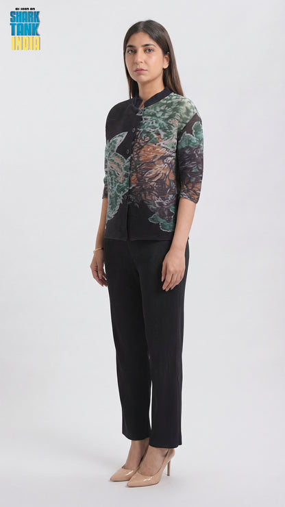 Woman wearing a patterned top and black pants on a white background