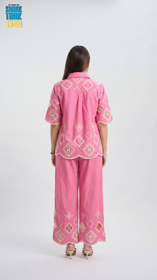 Woman wearing a pink embroidered outfit on a white background