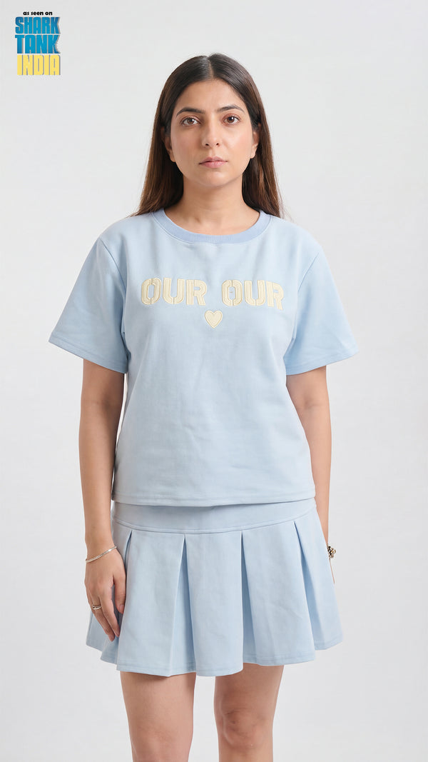Woman wearing a light blue t-shirt and skirt with 'Glee Club' text on a white background
