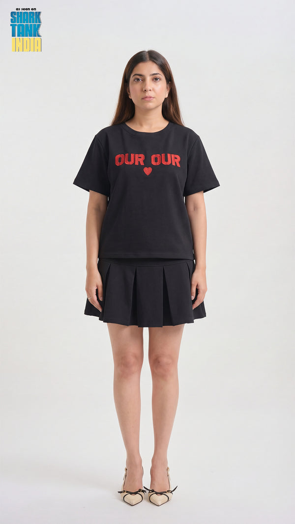 Person wearing a black t-shirt with 'OUR' printed on it, standing against a white background.