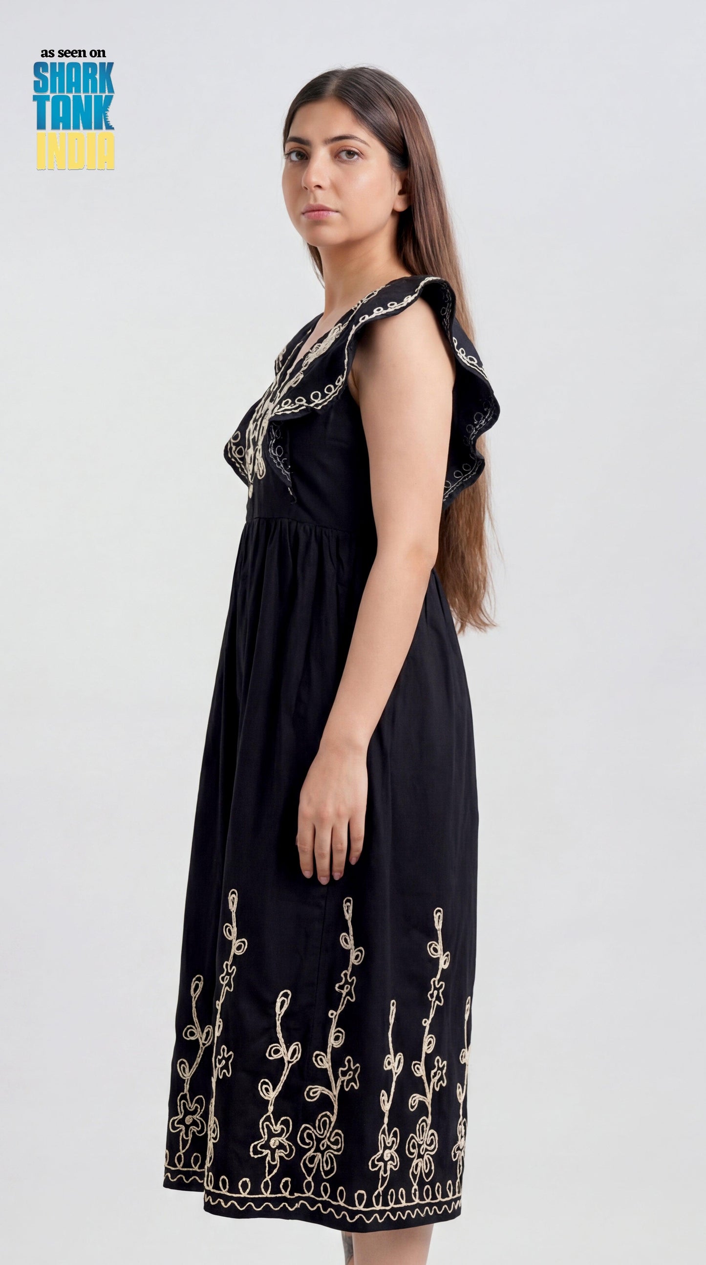 Woman wearing a black dress with floral embroidery on a white background