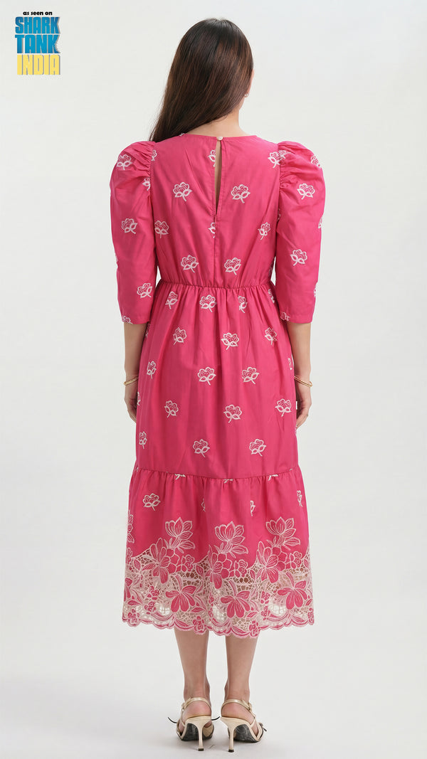 Woman wearing a pink dress with white floral patterns on a white background